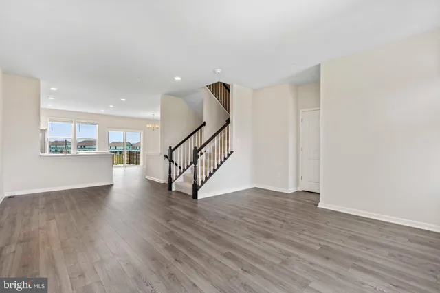 a view of empty room with wooden floor and stairs