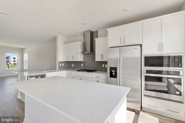 a kitchen that has a refrigerator a stove and white cabinets