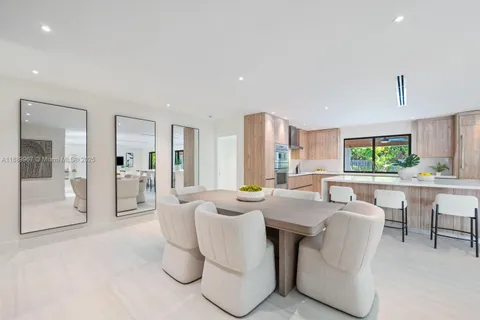 a dining room with furniture a large window and a kitchen view