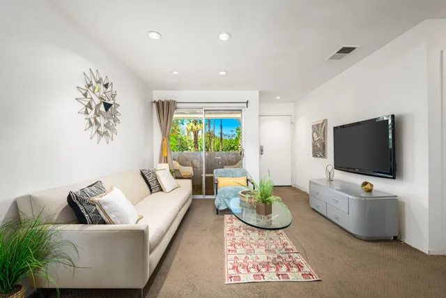 a living room with furniture a flat screen tv and a large window