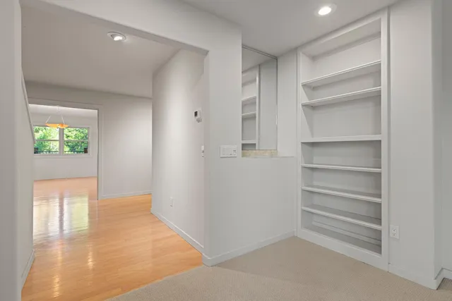 an empty room with wooden floor and kitchen view