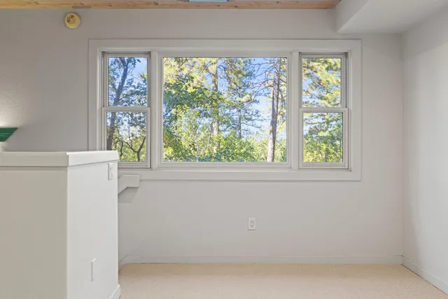 an empty room with windows and chandelier fan