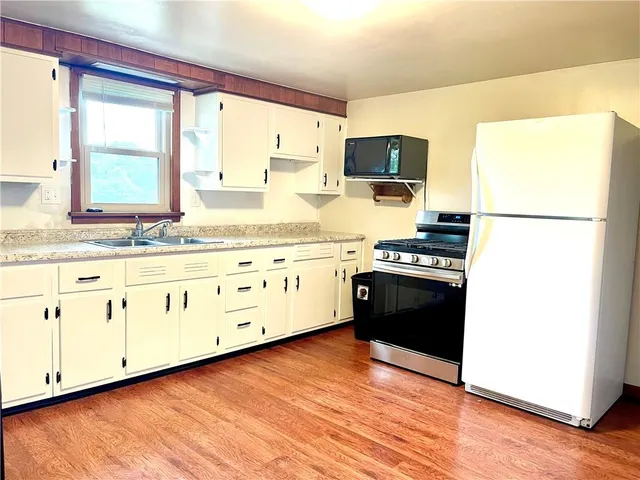a kitchen with granite countertop a stove a sink and a refrigerator