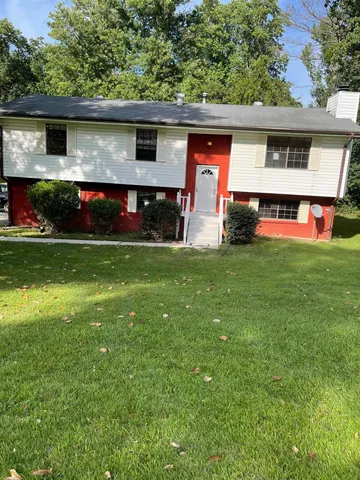 a front view of house with yard and trees in the background