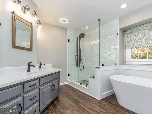 a bathroom with a tub sink double vanity granite and a shower