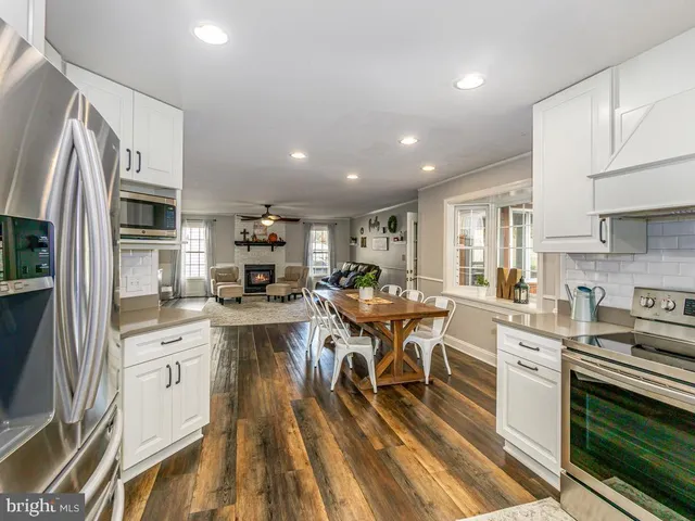 a kitchen with stainless steel appliances a stove a sink dishwasher a oven with white cabinets and wooden floor