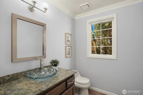 a bathroom with a granite countertop sink a mirror and a toilet