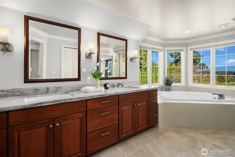 a bathroom with a tub double sink window and mirror