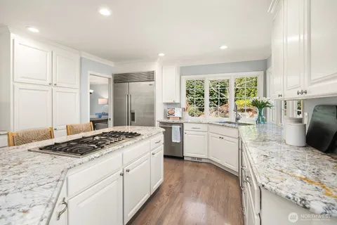 a kitchen with a stove a sink a refrigerator and white cabinets with wooden floor