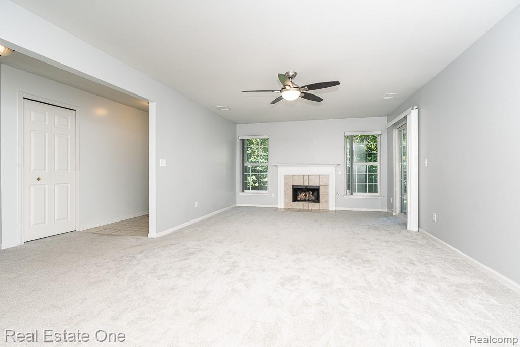 3491 Tremonte Circle Rochester, MI 48306 - Photo 4 of 42 Carpeted main living space with a fireplace, ceiling fan, and multiple windows
