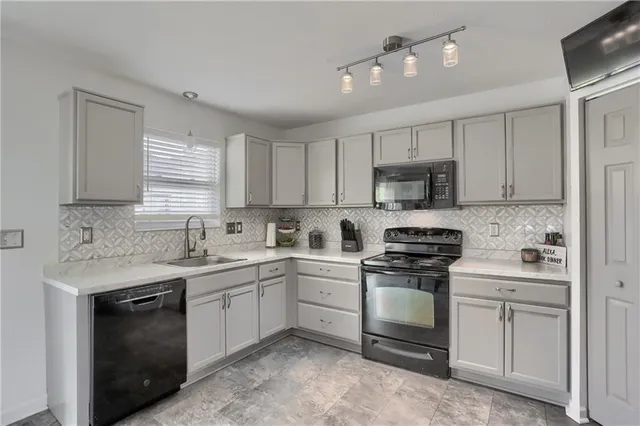 a kitchen with white cabinets appliances a sink and a window
