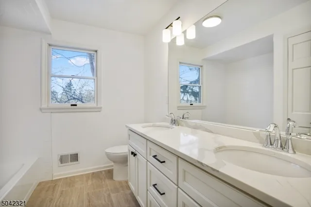 a bathroom with a granite countertop sink a toilet and a mirror