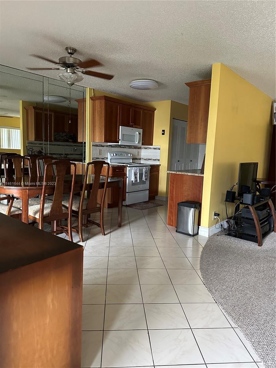 14711 Edna Way Delray Beach, FL 33484 - Photo 5 of 23 a living room with stainless steel appliances lots of white furniture a rug a fireplace and a counter top space