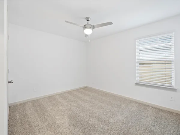 an empty room with a window and a fan