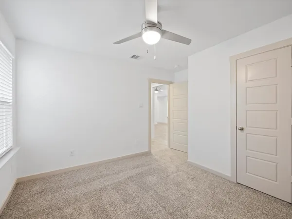 an empty room with a fan & a window