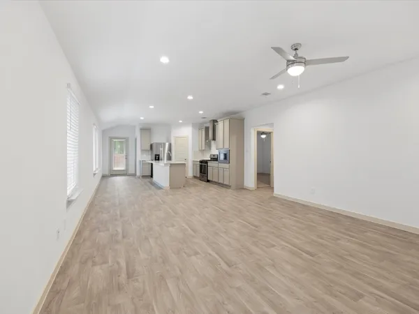 an empty room with wooden floor sink and windows