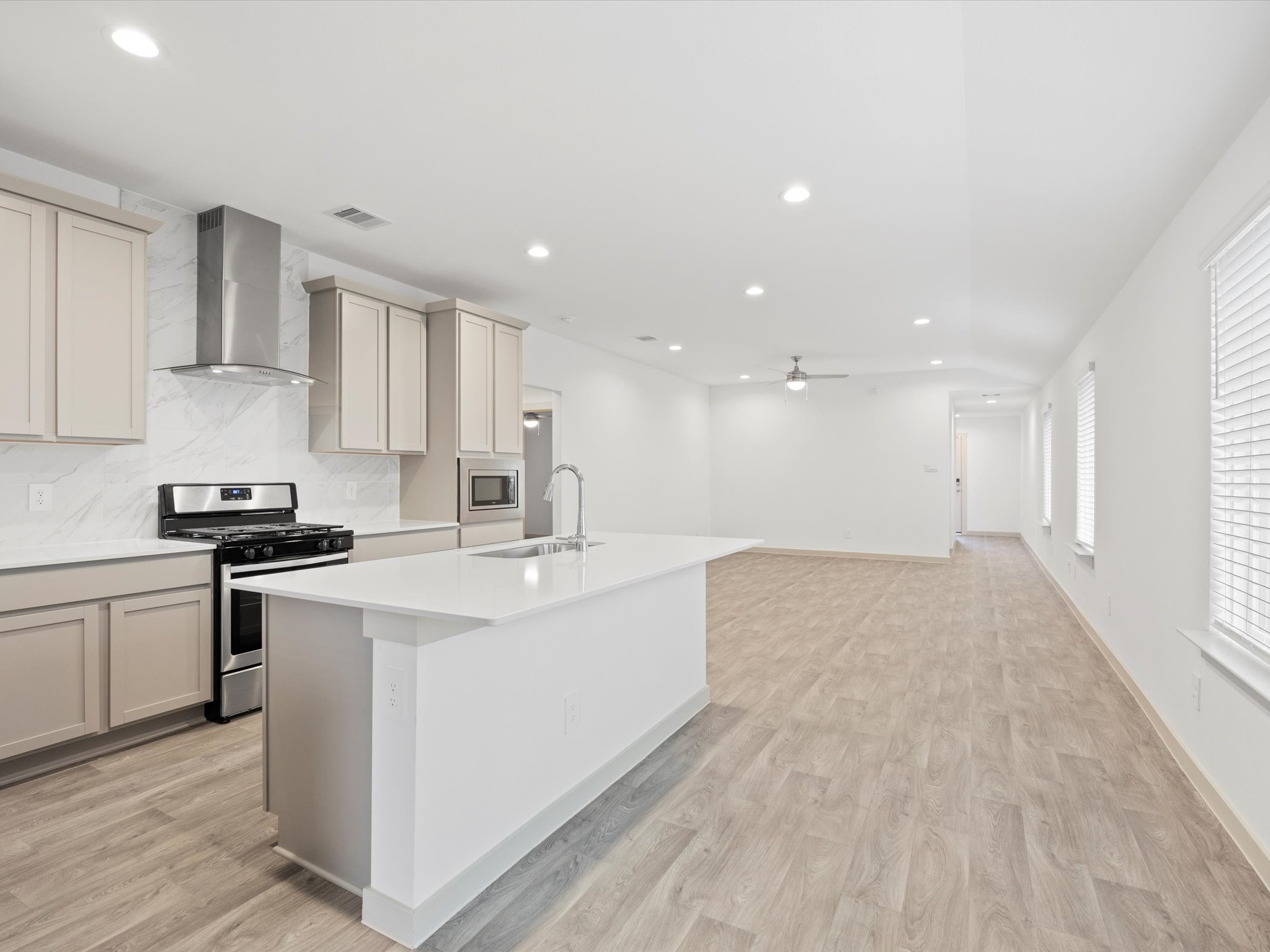 12733 Ermine Street Houston, TX 77047 - Photo 6 of 15 a large white kitchen with stainless steel appliances granite countertop a stove a sink a refrigerator and white cabinets with wooden floor