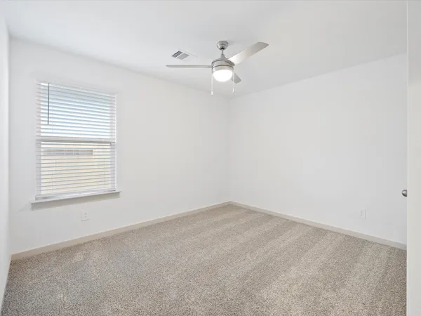 an empty room with a window and ceiling fan