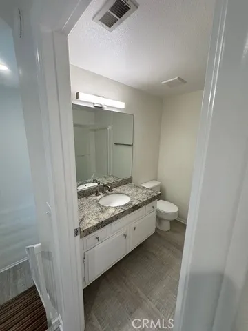 a bathroom with a granite countertop sink a toilet and a mirror