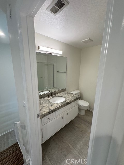 4455 West Coast Highway, Unit 23 Newport Beach, CA 92663 - Photo 13 of 30 a bathroom with a granite countertop sink a toilet and a mirror