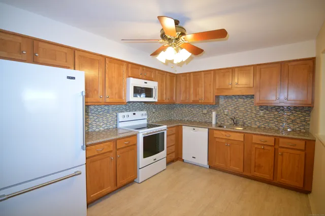 a kitchen with stainless steel appliances granite countertop cabinets a sink a stove a refrigerator a washer dryer and cabinets