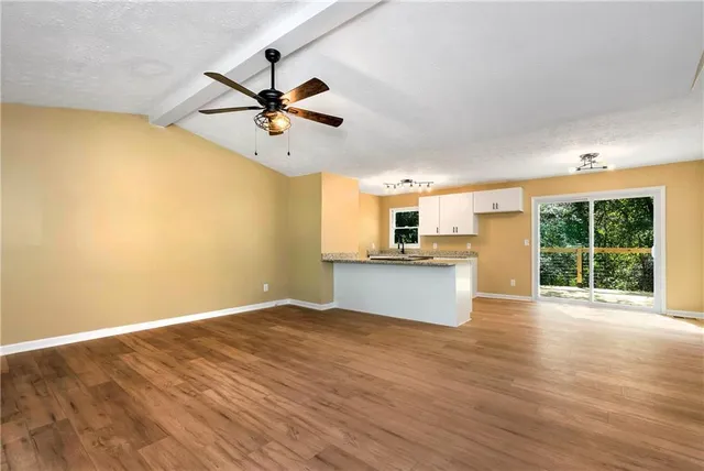 a view of an empty room with window and wooden floor