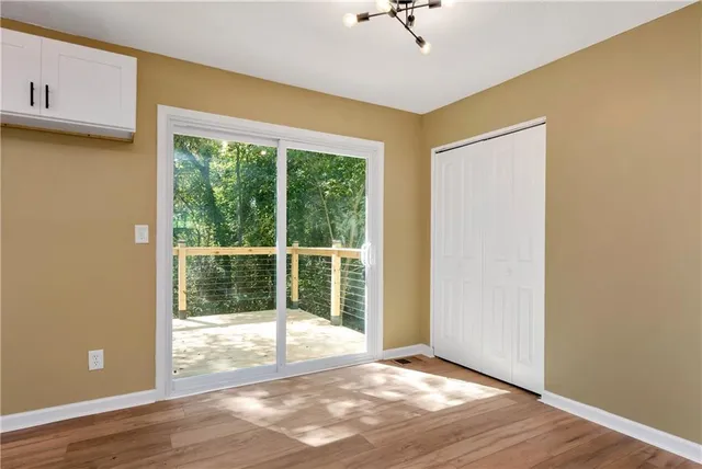 a view of an empty room with a window and wooden floor