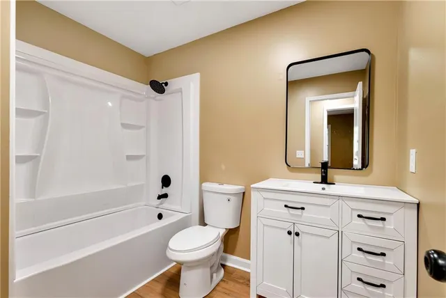 a bathroom with a toilet a sink a mirror a bathtub and vanity