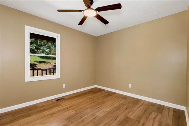 an empty room with a window and a fan