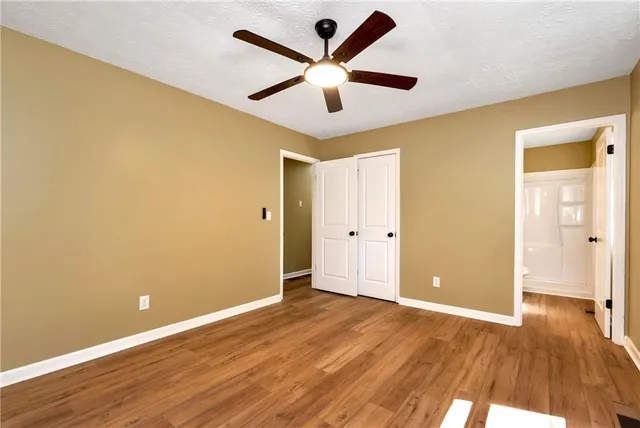 an empty room with wooden floor and ceiling fan