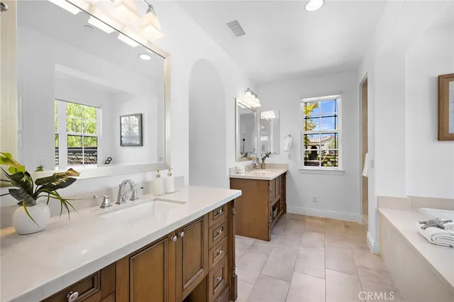 a bathroom with a granite countertop sink a bathtub and next to a window