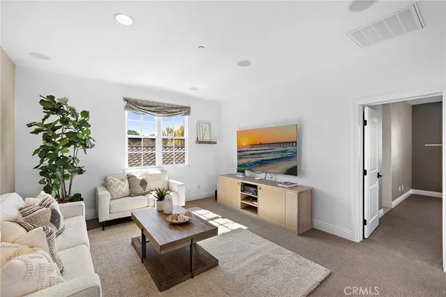 a living room with furniture kitchen view and a wooden floor