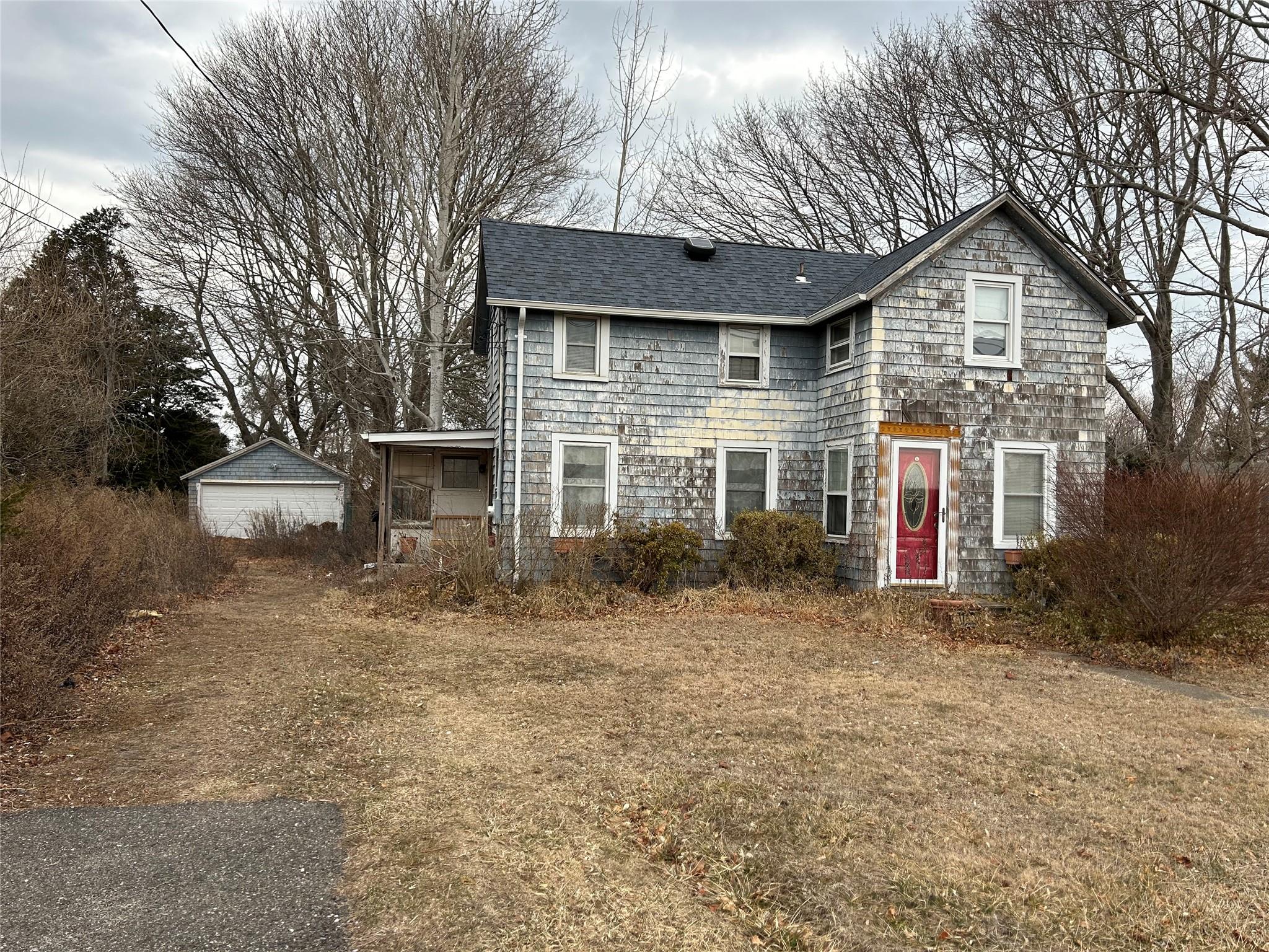 View of front of home featuring a detached garage, an outdoor structure, and roof with shingles