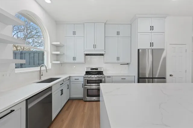 a kitchen with stainless steel appliances granite countertop a stove a sink and white cabinets