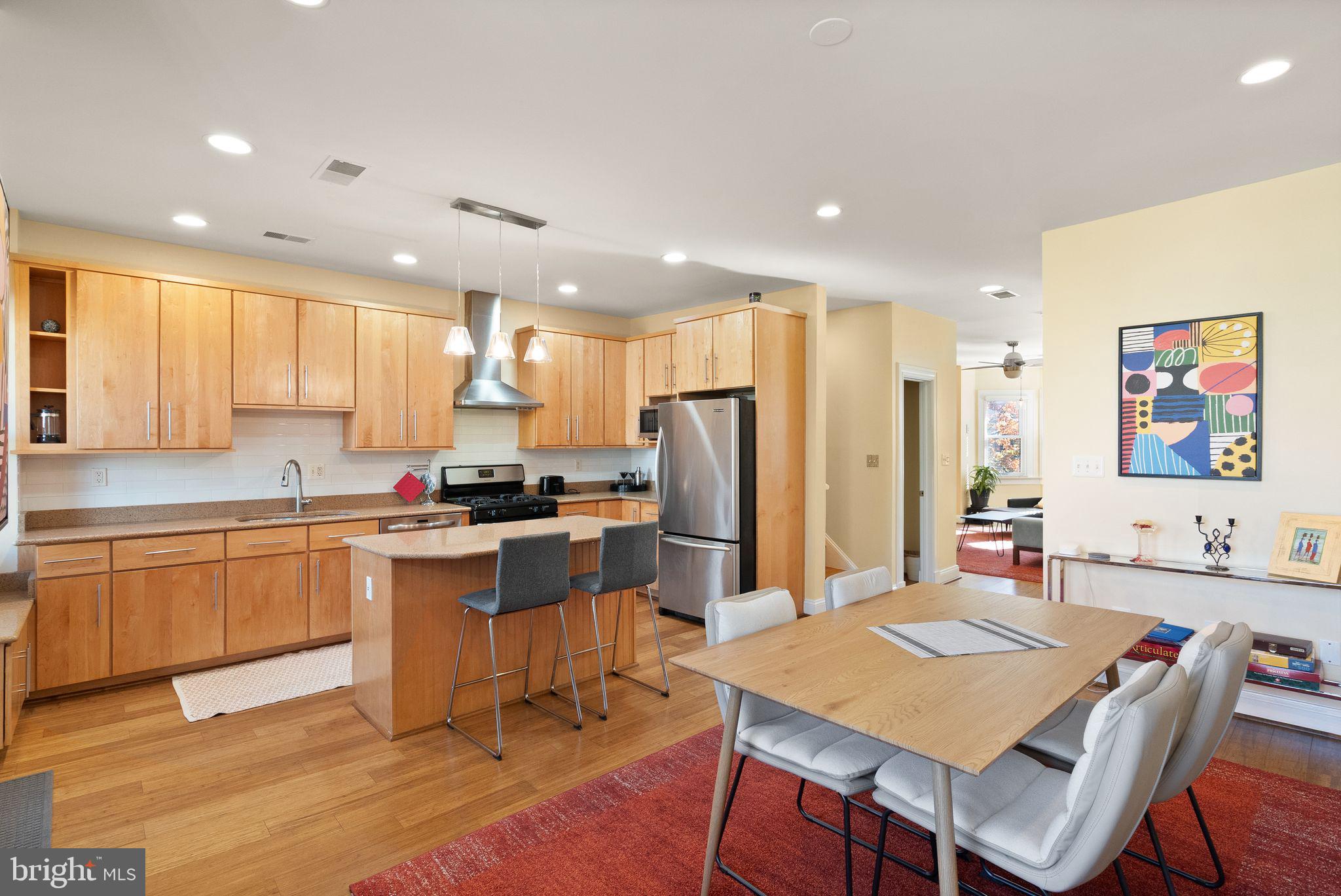 1335 Harvard Street Northwest, Unit PH2 Washington, DC 20009 - Photo 9 of 34 a kitchen with stainless steel appliances granite countertop a table chairs sink refrigerator and cabinets