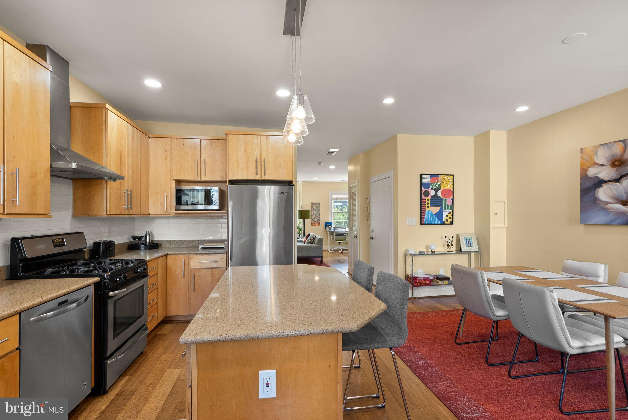 1335 Harvard Street Northwest, Unit PH2 Washington, DC 20009 - Photo 10 of 34 a kitchen with stainless steel appliances granite countertop a stove a refrigerator a kitchen island with chairs and white cabinets