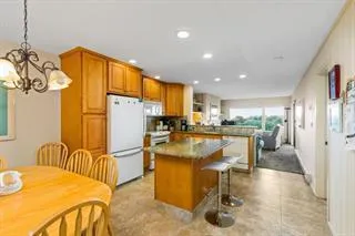 a living room with stainless steel appliances furniture a rug and a kitchen