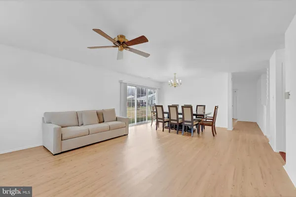an empty room with wooden floor ceiling fan and windows