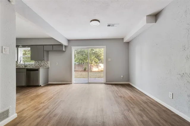 a view of an empty room with window and wooden floor