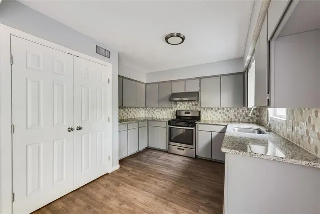 a kitchen with granite countertop a sink cabinets and stainless steel appliances