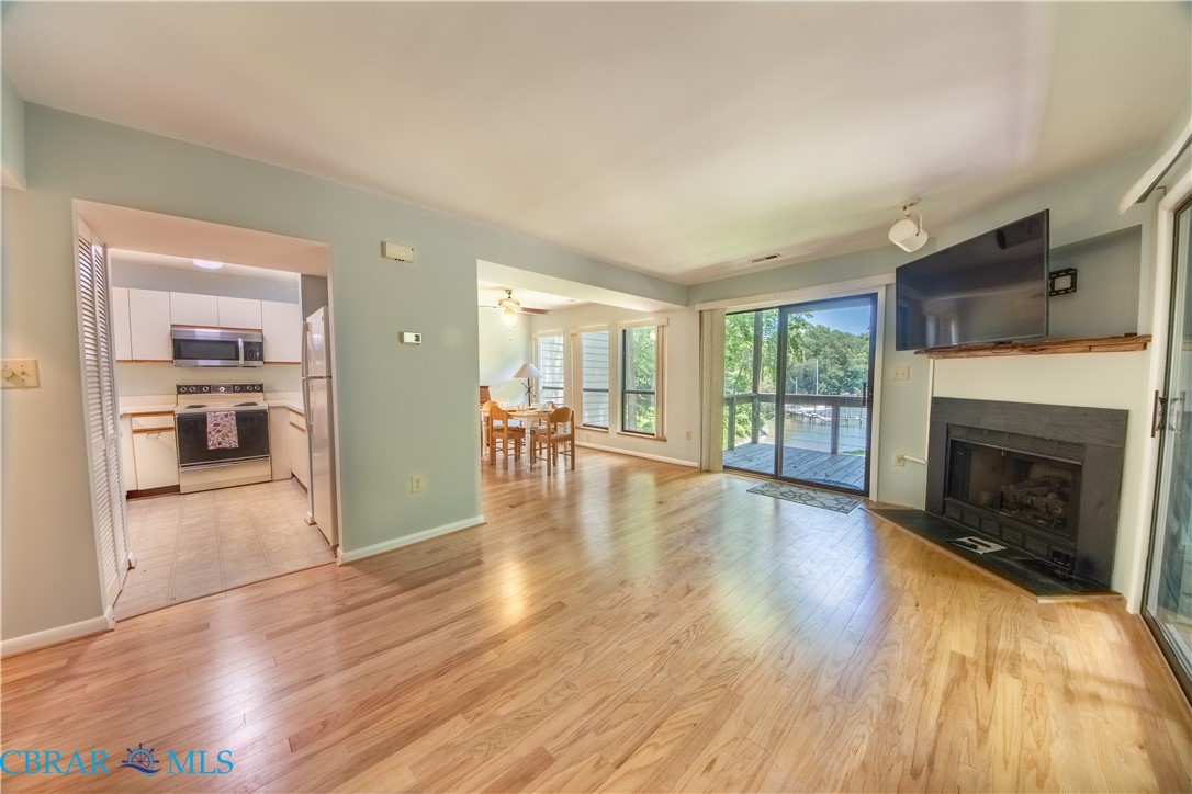 54 Villa Ridge Drive, Unit C Hartfield, VA 23071 - Photo 21 of 45 Unfurnished living room with light wood finished floors, a fireplace with raised hearth, and ceiling fan