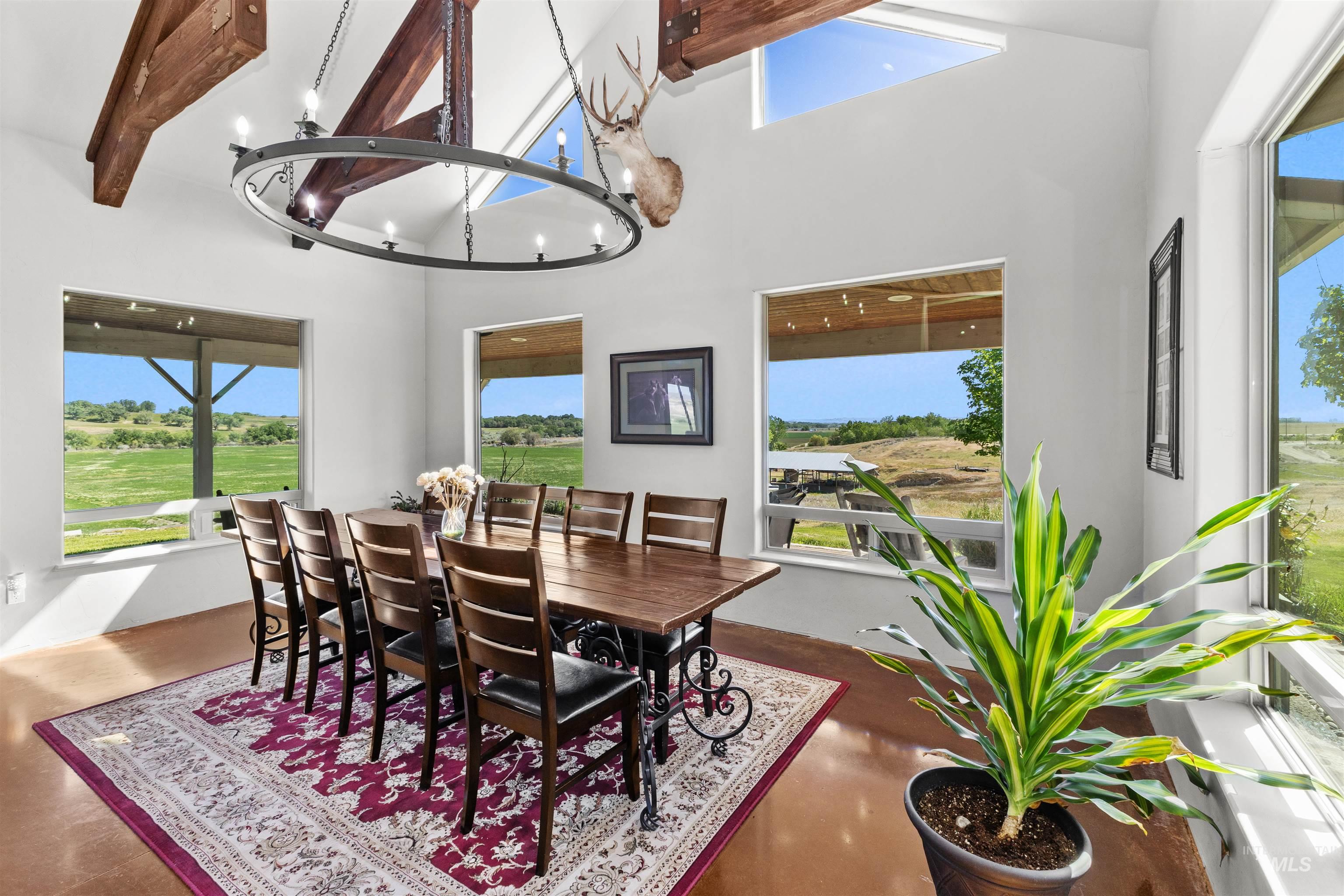1030 Desert Glen Road Adrian, OR 97901 - Photo 15 of 47 Vaulted ceiling dining area featuring exposed wood beams, an iron chandelier, and multiple windows providing natural light