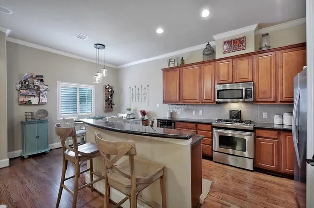 a kitchen with stainless steel appliances granite countertop a stove top oven a sink dishwasher and cabinets with wooden floor