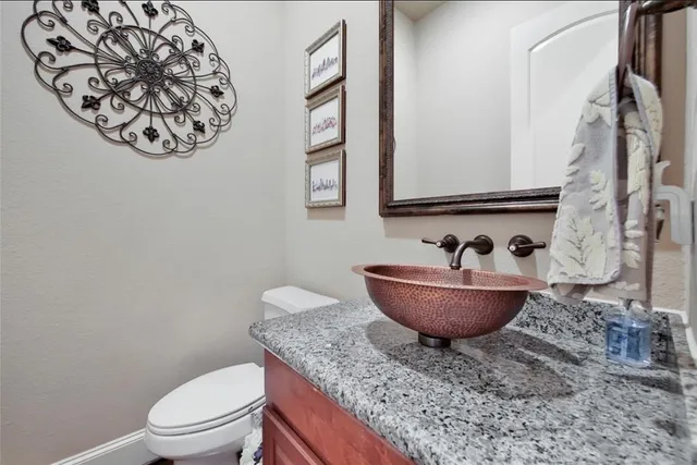 a bathroom with a granite countertop sink and a toilet