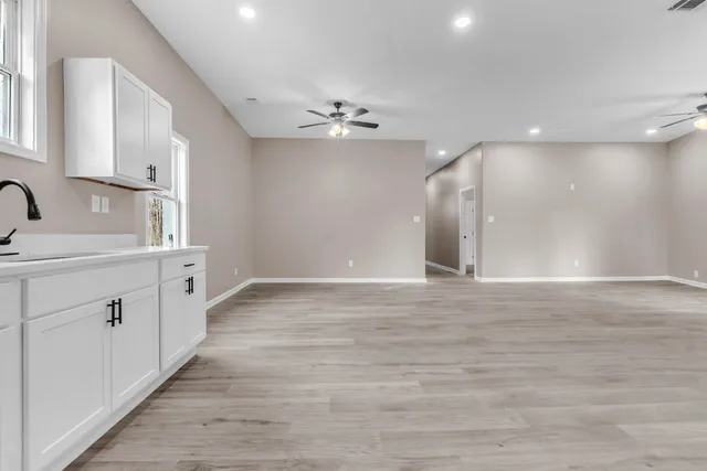 a view of a hallway with wooden floor and a bathroom