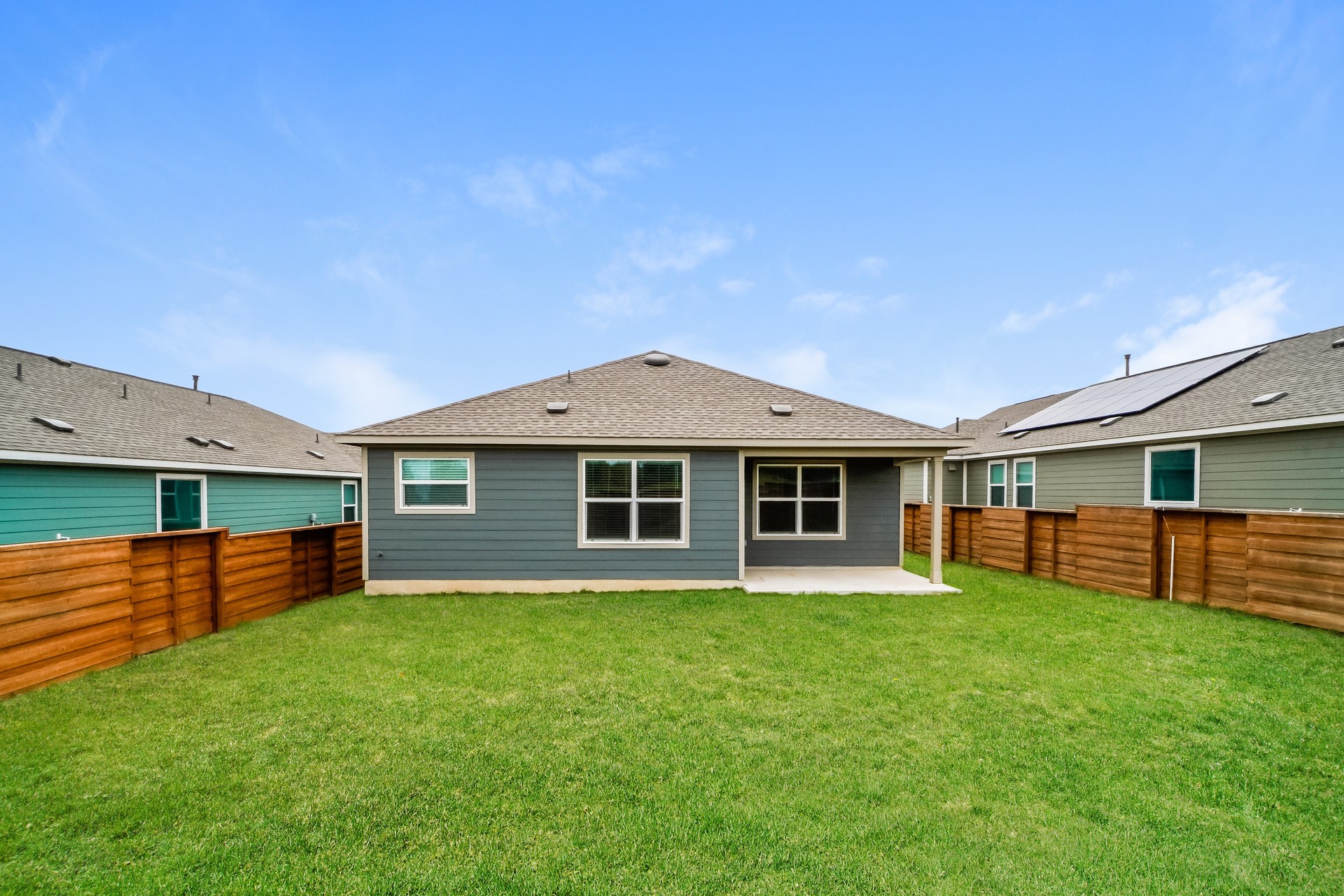 341 Madrid Kyle, TX 78640 - Photo 4 of 27 A deep blue house with a gray roof and concrete patio offers a private fenced yard.