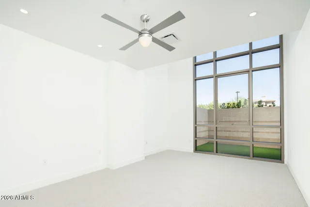 an empty room with wooden floor and a ceiling fan