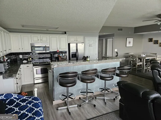 a kitchen with stainless steel appliances kitchen island granite countertop a stove and white cabinets