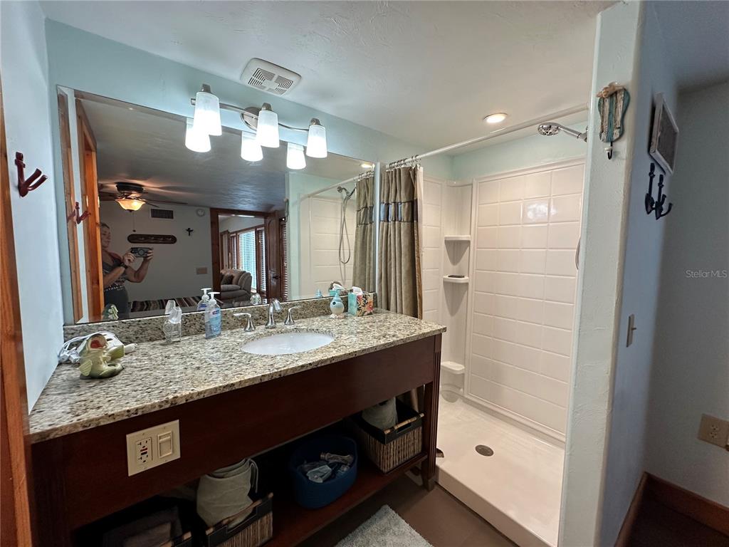 56315 Hickory Road Astor, FL 32102 - Photo 20 of 31 a bathroom with a granite countertop sink a large mirror and shower