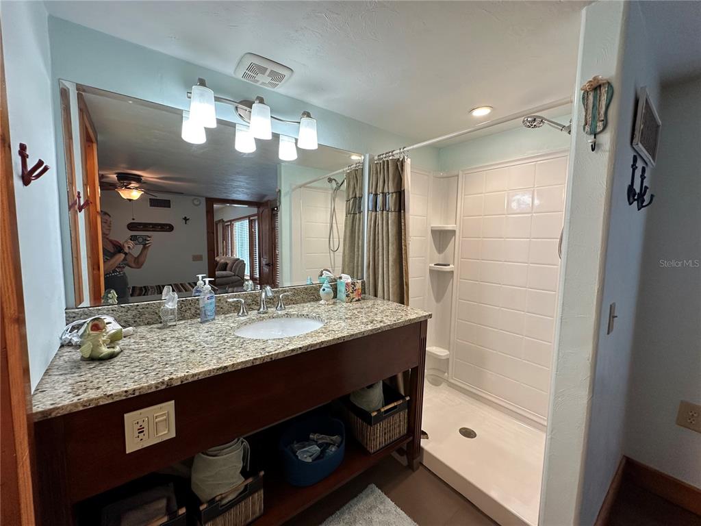 56315 Hickory Road Astor, FL 32102 - Photo 21 of 31 a bathroom with a granite countertop sink a large mirror and shower